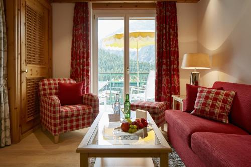 a living room with red chairs and a table with a bowl of fruit at Hotel Walther - Relais & Châteaux in Pontresina