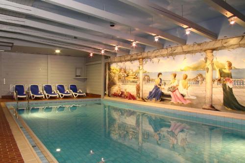 a large swimming pool with blue chairs around it at Chalét zum Kurfürst in Oberschleißheim