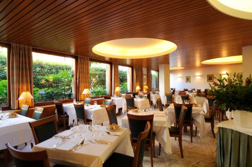 un restaurante con mesas y sillas blancas y ventanas en Hotel Majestic, en Alassio