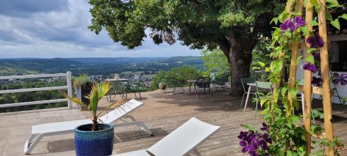 a deck with chairs and tables and a tree at Le Clos Des Etoiles in Le Bugue