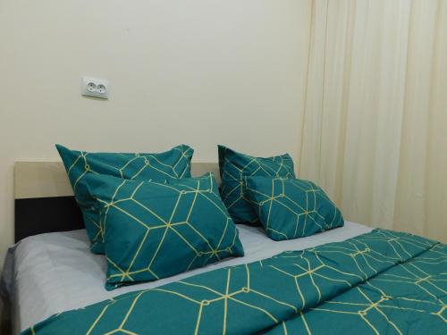 a bed with blue and yellow pillows on it at Апартамент в курзоне пр Кирова 7 in Pyatigorsk