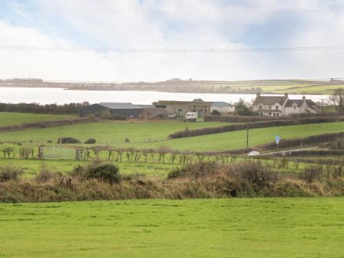 a green field with a farm and a body of water at Y Bwthyn in Amlwch