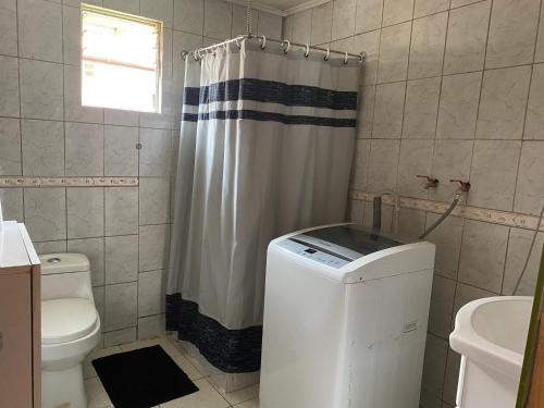 a bathroom with a toilet and a shower curtain at Cabaña Cris in Cochrane