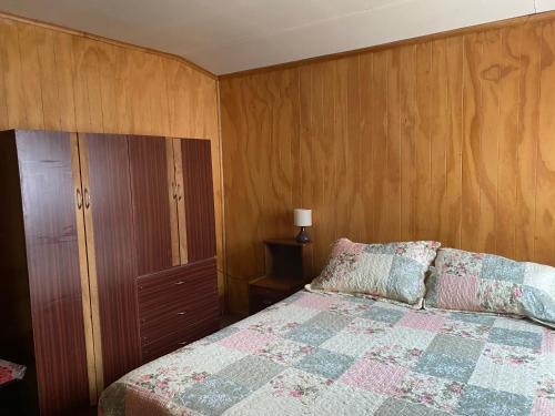 a bedroom with a bed and a wooden wall at Cabaña Cris in Cochrane