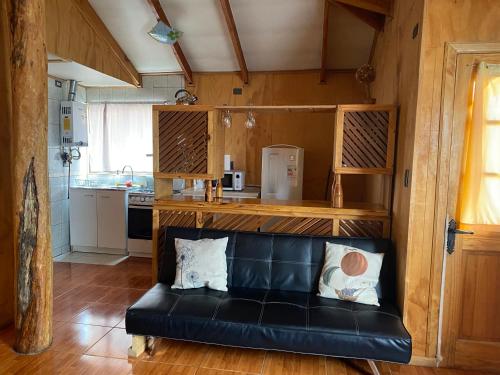 a black leather couch in a room with a kitchen at Cabaña Cris in Cochrane