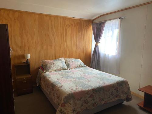 1 dormitorio con cama y ventana en Cabaña Cris, en Cochrane