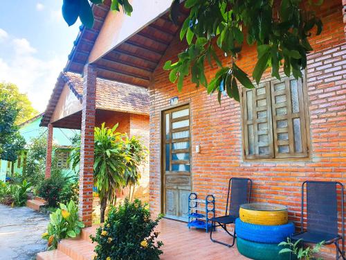 une maison en briques avec un banc et une table devant elle dans l'établissement Thuy Tien Ecolodge, à Cat Tien