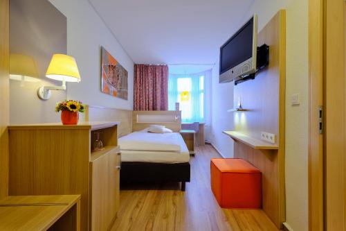 a hotel room with a bed and a tv at Hotel VICTORIA Nürnberg in Nürnberg