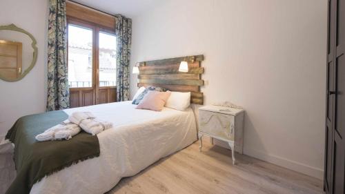 a bedroom with a bed with white sheets and a window at Apartamento Pasaje del Barco by Toledo AP in Toledo