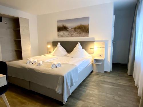 1 dormitorio con 1 cama con sábanas y almohadas blancas en Hotel Kranenborgh Steinhude am Meer en Steinhude