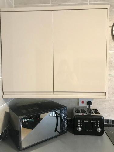 a microwave and a toaster oven under a cabinet at Towan Beach Holiday Flat in Newquay