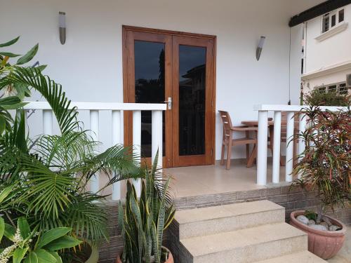 a house with a wooden door and stairs with plants at La Maison Hibiscus Self Catering Accommodation in Beau Vallon