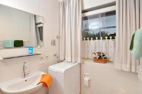 MunkmarschにあるSylter-Wattkojeの白いバスルーム(洗面台、トイレ付)、窓が備わります。