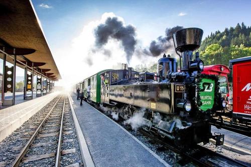 a steam engine train on the tracks at a train station at Wellness Chalet Bell a Mur in Murau