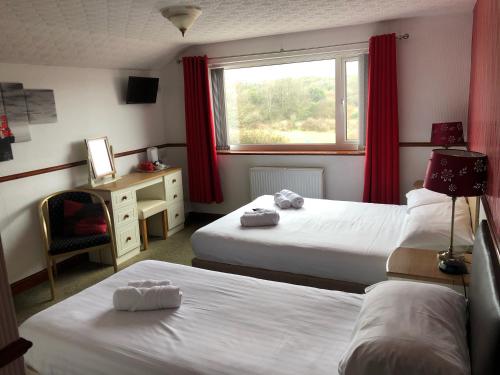 - une chambre avec 2 lits et une fenêtre avec des rideaux rouges dans l'établissement Boathouse Hotel, à Holyhead