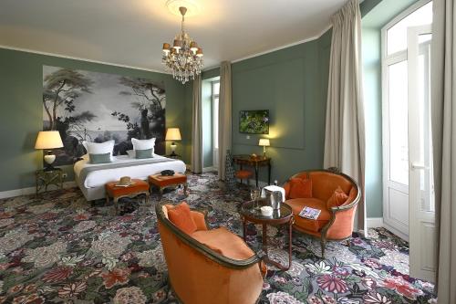 a bedroom with a bed and chairs and a chandelier at Grand Hôtel Henri - Teritoria in LʼIsle-sur-la-Sorgue