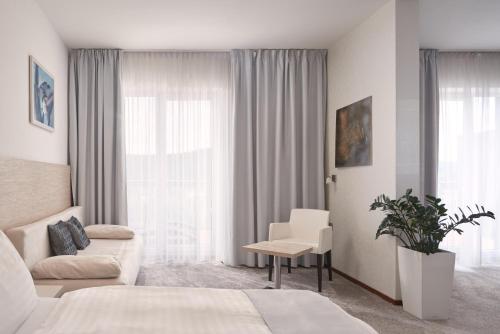 a bedroom with a bed and a couch and a window at Maximus Resort in Brno