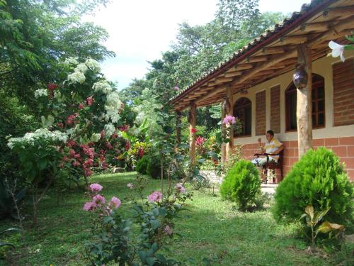 a woman sitting on a porch of a house with flowers at Ecolodge Blue Morpho in Cárdenas