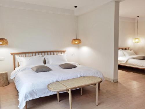a bedroom with a large white bed and a bench at Riverside Retreat Hotel in Yangshuo