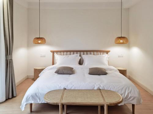 a bedroom with a large white bed and two lamps at Riverside Retreat Hotel in Yangshuo