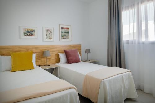 a hotel room with two beds and a window at Villas Altos de Lanzarote in Playa Blanca