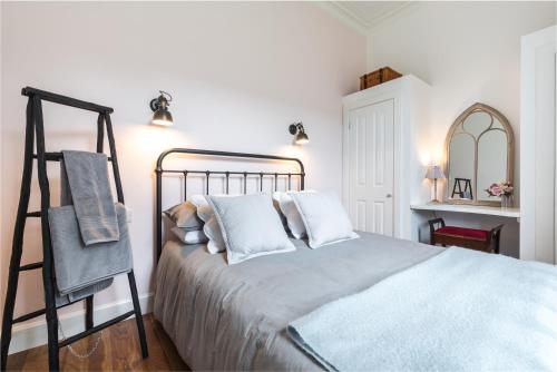 a bedroom with a bed with white pillows and a ladder at Newly renovated stunning apartment in Stockbridge in Edinburgh