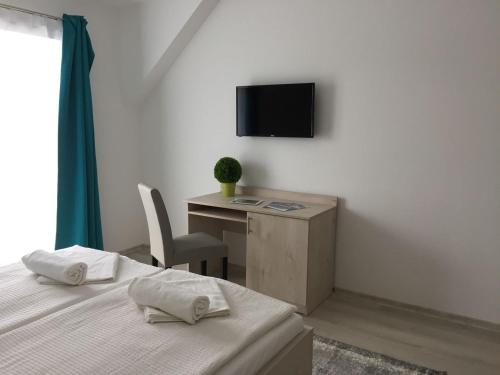 a bedroom with a bed and a desk and a television at Hotel Aqua in Komárom