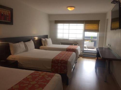 a hotel room with two beds and a window at Hotel Britania Miraflores in Lima
