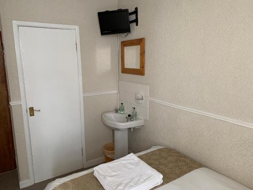 a small bathroom with a sink and a bed at Sharn Bek Hotel in Blackpool