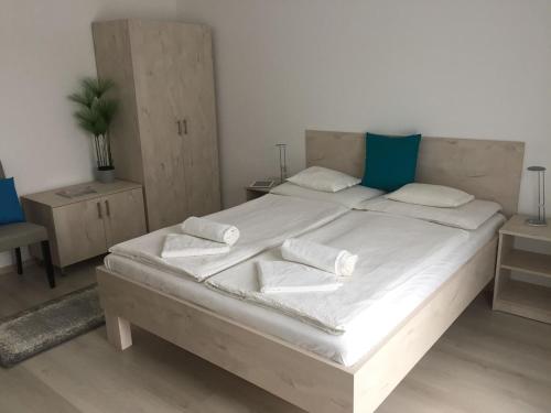 a bedroom with a large bed with white sheets and blue pillows at Hotel Aqua in Komárom