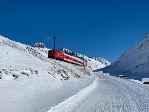 a red train traveling down a snow covered mountain at Casa Restelli OG - nahe Andermatt Gotthard in Gurtnellen