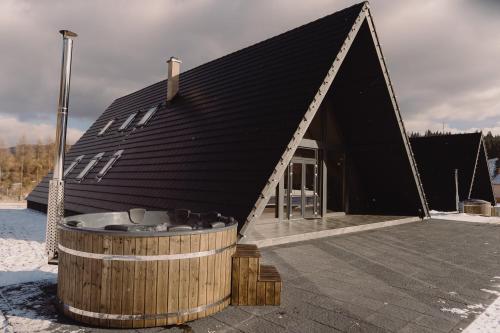 a black roofed house with a hot tub in front at Treeline Cabins in Cădăreşti
