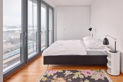 een witte slaapkamer met een bed en een groot raam bij Designer Condo in Karlín by Prague Days in Praag