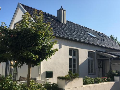 ein weißes Haus mit einem Baum davor in der Unterkunft Groot Huus in Norderney