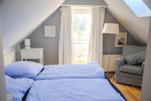 ein Schlafzimmer mit einem Bett und einem Stuhl und einem Fenster in der Unterkunft Groot Huus in Norderney