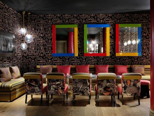 a room with a bar with chairs and mirrors at The Soho Hotel, Firmdale Hotels in London