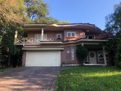 a brick house with a garage and a driveway at Casa do Bosque, espaçosa e confortável em condominio espetacular, 5 min centro! in Gramado