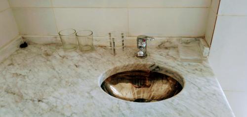 a dirty bathroom with a sink and two glasses on the floor at Departamento Yokavil in Santa María