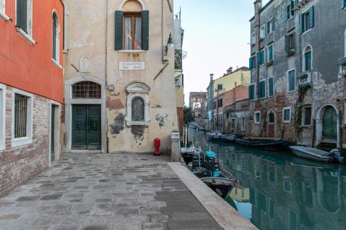 a narrow canal in a city with buildings at Canaletto Apartments in Venice