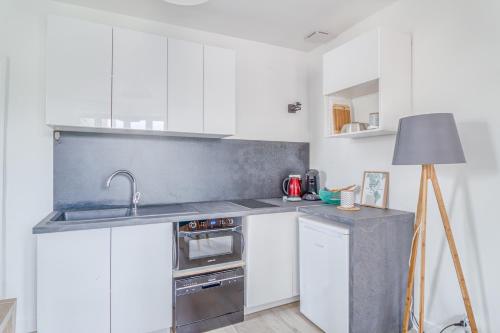 a white kitchen with a sink and a stove at Freedomus Marne-la-Vallée "Le 12" in Crecy la Chapelle