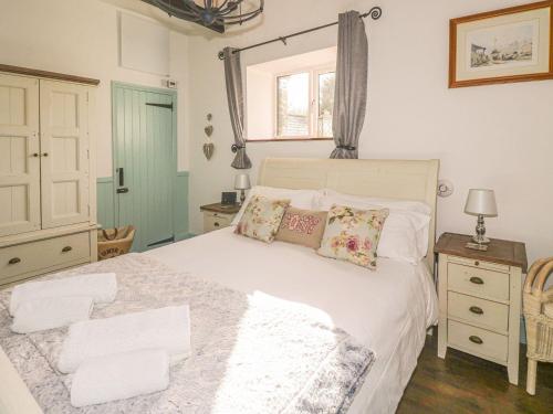 a bedroom with a white bed with pillows and a window at Nightingale Cottage in Liskeard