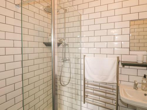 a white tiled bathroom with a shower and a sink at Nightingale Cottage in Liskeard