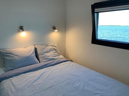 um quarto com uma cama e vista para a água em Houseboat Earebarre - Waterrijck Sneekermeer, Sneek - Offingawier em Offingawier