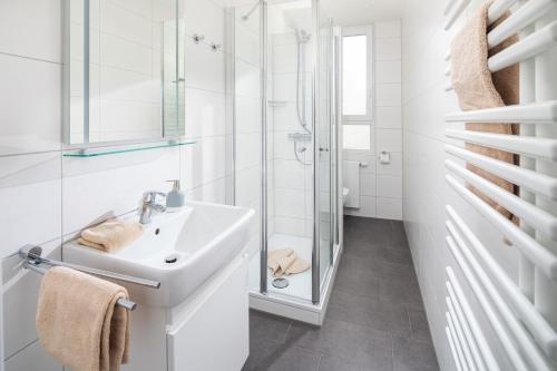 uma casa de banho branca com um lavatório e um chuveiro em Haus Kluin Wohnung 8 em Norderney