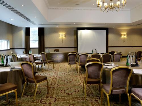 a conference room with tables and chairs and a projection screen at Macdonald Berystede Hotel & Spa in Ascot