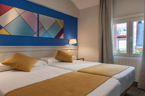 two beds in a hotel room with a painting on the wall at Hotel Hito in Vitoria-Gasteiz