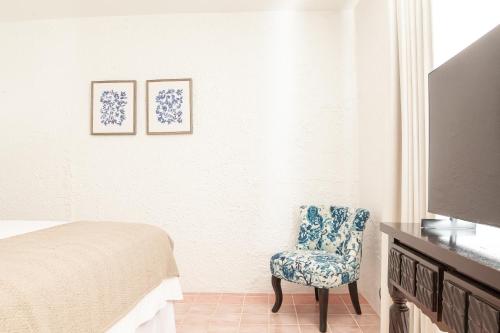a bedroom with a bed and a chair and a tv at Angeli Gardens Boutique Hotel in San Pedro Sula
