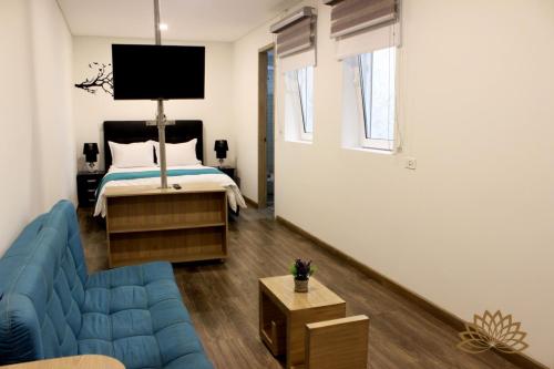 Una sala de estar con una cama y un sofá azul. en Apartahotel Boutique Central, en Bogotá