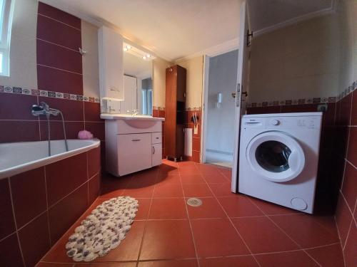 a bathroom with a washing machine and a bath tub at Arjana & Nelaj Apartments in Ksamil
