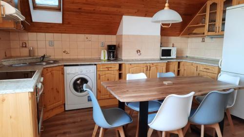 a kitchen with a wooden table and white chairs at Apartmány u Jiroušů in Rokytnice nad Jizerou